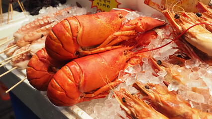 Freshly cooked lobsters  displayed on ice at a seafood market stall.