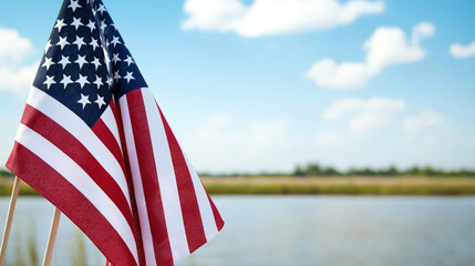 American flag waving by serene lake under blue sky with clouds