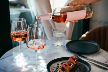 Pouring rose wine at a dinner party with friends in a bar or restaurant.