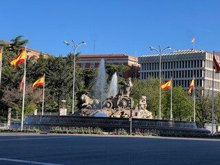 Majestic fountain in the city center surrounded by vibrant flags and lush greenery, showcasing a...