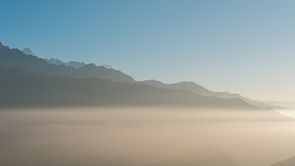 TADAPANI, NEPAL - JANUARY 11, 2025: Morning sunlight highlights the majestic hills covered in fog, showcasing nature's beauty and serenity, relaxation background.