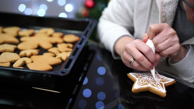 Confectioner draws icing patterns on star shaped gingerbread cookies