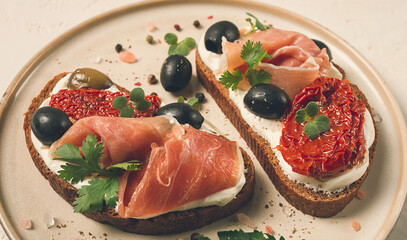 sandwiches with cheese and prosciutto, dried tomatoes and olives, breakfast on a plate,