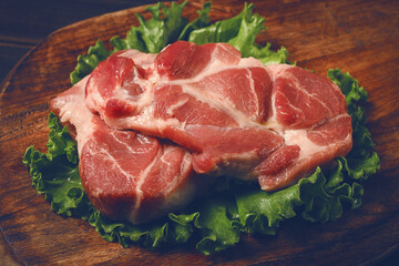 raw pork steak, two pieces, on a wooden background,