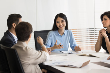 Interactive discussion. Happy smiling Asian woman team leader project manager hold open dialogue on...