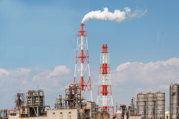 Smoke rising from industrial factory during daytime with clear blue skies