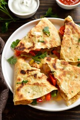 Chicken quesadilla with fresh vegetables on wooden table