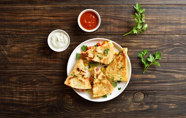 Chicken quesadilla with fresh vegetables on wooden table