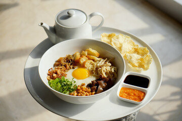 Chicken porridge, isolated on the breakfast concept. Porridge complete with shredded chicken, sunny side up, chips, leeks, and fried onions.