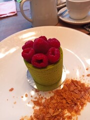 Matcha mousse dessert topped with raspberries