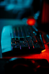 Vivid neon gaming setup featuring a backlit keyboard and gaming mouse in a dimly lit work...