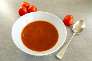 homemade tomato soup in white bowl with fresh tomatoes  
