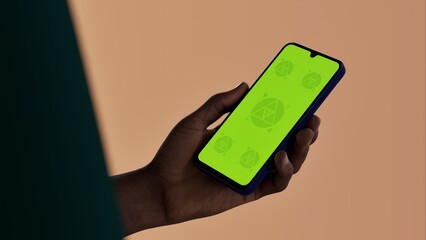 Black African-American middle aged male using smartphone with a blank green screen. Mobile app video mockup. Vertical phone orientation