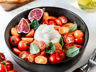 Delicious burrata cheese with fresh tomatoes, spinach, figs and olive oil.