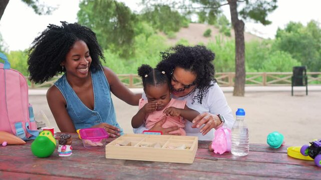 Multigenerational african american family sharing playful moments at outdoor park bench, connecting through joyful interaction and tender bonding