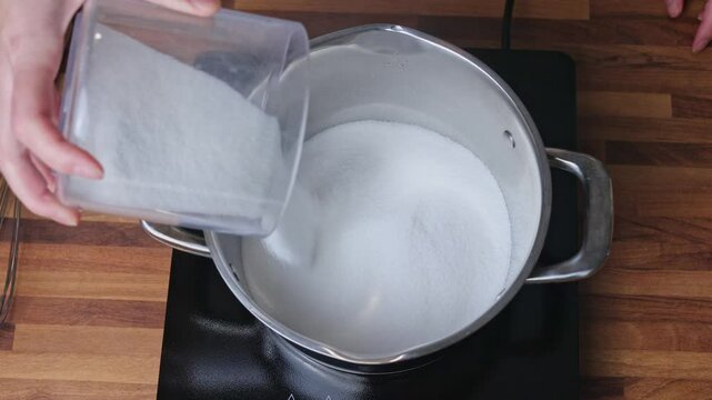 Preparing sugar syrup for cooking tangerine jam in a saucepan on the stove in a home kitchen