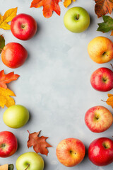 Colorful autumn apples and leaves arranged on light background