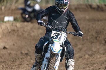 Motocross rider wearing black and white driving on dirt track