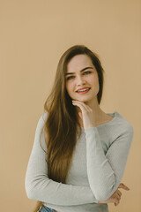 Obraz premium Smiling Woman With Long Hair in Casual Attire Against a Beige Background