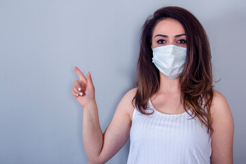  woman wearing in medical face mask and pointing with forefinger away