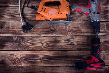 construction carpentry tools electric corded jigsaw cordless drill and wood sander on wooden background