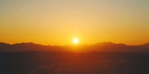 Obraz premium A stunning sunset paints the sky in warm orange and yellow hues. The sun dips behind distant mountains, creating a serene and peaceful ambiance. Ideal for nature lovers or inspirational themes. AI