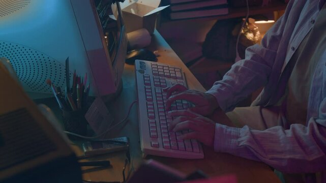 Midsection shot of unknown male web developer writing code on retro computer with mechanical keyboard at messy table