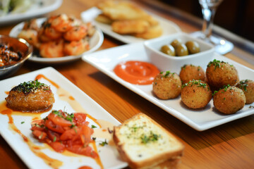 A vibrant selection of tapas on small plates, featuring savory olives, fried calamari, meatballs, Manchego cheese, and garlic shrimp, creating an inviting Spanish appetizer spread