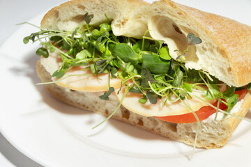 Obraz premium A macro shot of a fresh turkey and microgreens sandwich on crispy ciabatta, highlighting the natural textures of ingredients.