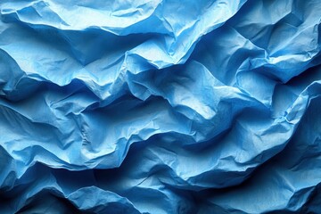 Fototapeta premium Crumpled blue paper texture with intricate folds and shadows, showcasing depth and dimension in a creative composition