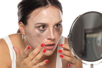 Young nervous woman applies face cleaning product before remove it on a white background