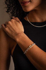 Woman wearing a black top showing off her matching necklace and bracelet.