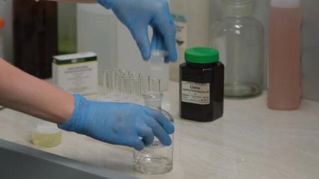 Scientist working with test tubes in laboratory, bottle labeled acetone