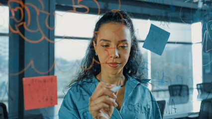 Young hispanic employee writing on colorful sticky notes. Smart businesswoman sharing marketing...