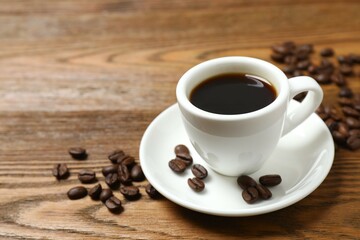 Cup of coffee with fresh coffee beans on wooden background
