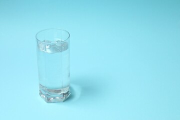 Transparent glass with water on blue background. Drinking clear water in the morning for health