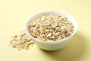 Composition with oatteal flakes on beige back ground. Cooking breakfast