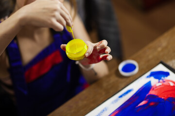 Female artist making an artistic painting with her hands. View from above.