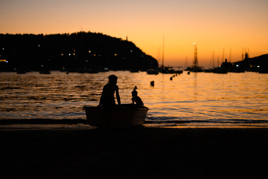 Silhouetted of Children on a Boat Against a Sunset Sky in Soller