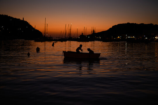 Silhouette of a children in boat at sunset on a harbor in Soller