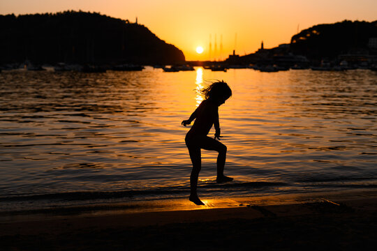 Silhouette of child playing at sunset by the seashore in Soller