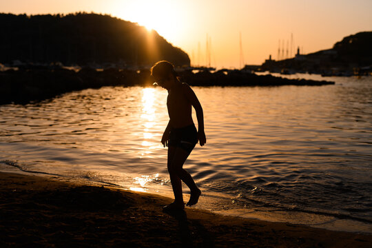 Silhouette of a Child Walking on the Beach at Sunset in Soller
