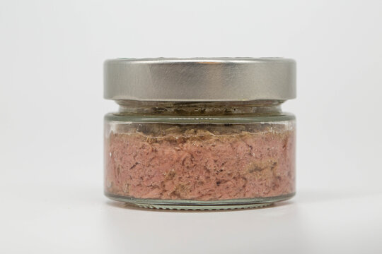 Glass jar with tuna pate and metal lid on light background