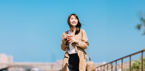春の街を歩く笑顔の女性・ビジネスウーマン