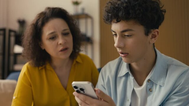 Adolescent son trying to help his mom with an app on her phone, tech support