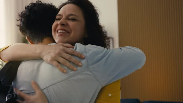 Happy mom embracing her teen son coming home from university, cherishing reunion