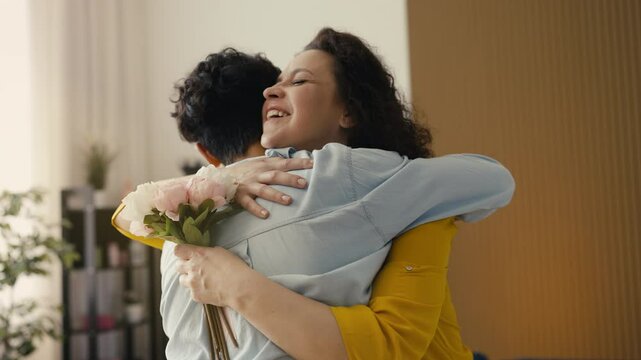 Caring teen son presenting flowers to his loving mom, Mother's Day gift