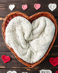 Fondo digital con canasta de mimbre con forma de corazón, adornos de corazón de crochet, sobre madera rústica en ambiente rústico