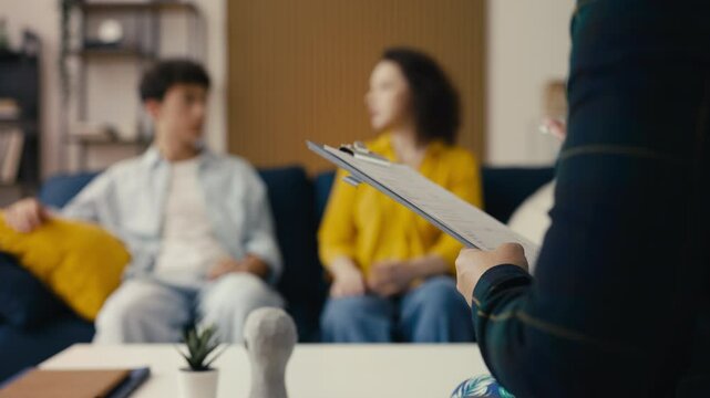 Teen psychologist attentively listening to a nervous teenage boy and his mother