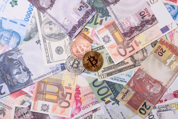 Round metal bitcoin on a background of paper banknotes of different currencies